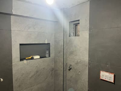 Duvarlar büyük ebat gri karoyla kaplandı. Sol duvarda siyah çerçeveli gömme niş; havalandırma penceresi karo içinde çerçevelendi.